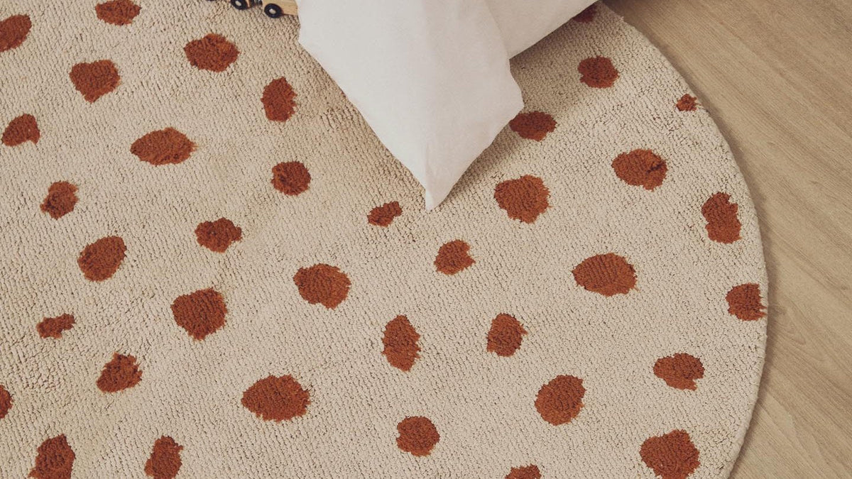 Tandani Kollektion von Kave Home: beiger Baumwollteppich mit orangem Gepard, Bodenkissen mit Elefant und Körbe
