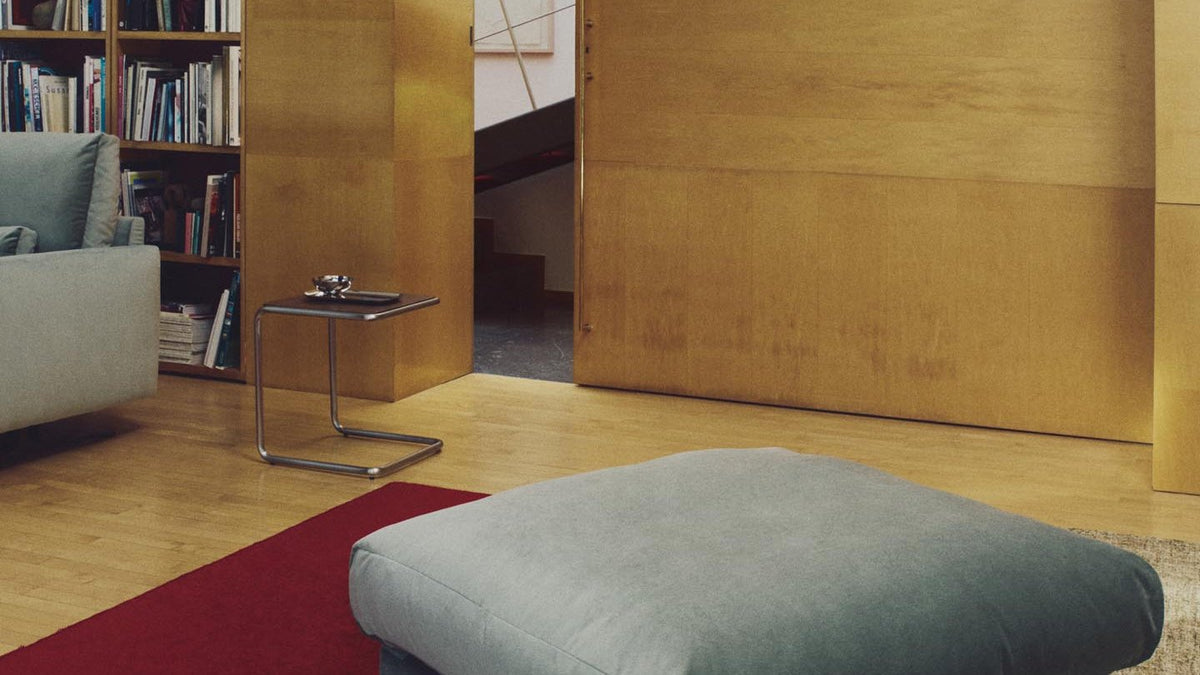 Veliro 2-Sitzer-Sofa von Kave Home in grünem Samt mit schwarzen Stahlbeinen, daneben die passende Fussablage