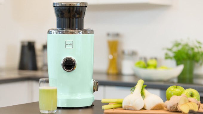 NOVIS Entsafter NewGen SX-3 VitaJuicer in verschiedenen Farben auf einer Küchenarbeitsfläche mit frischem Obst