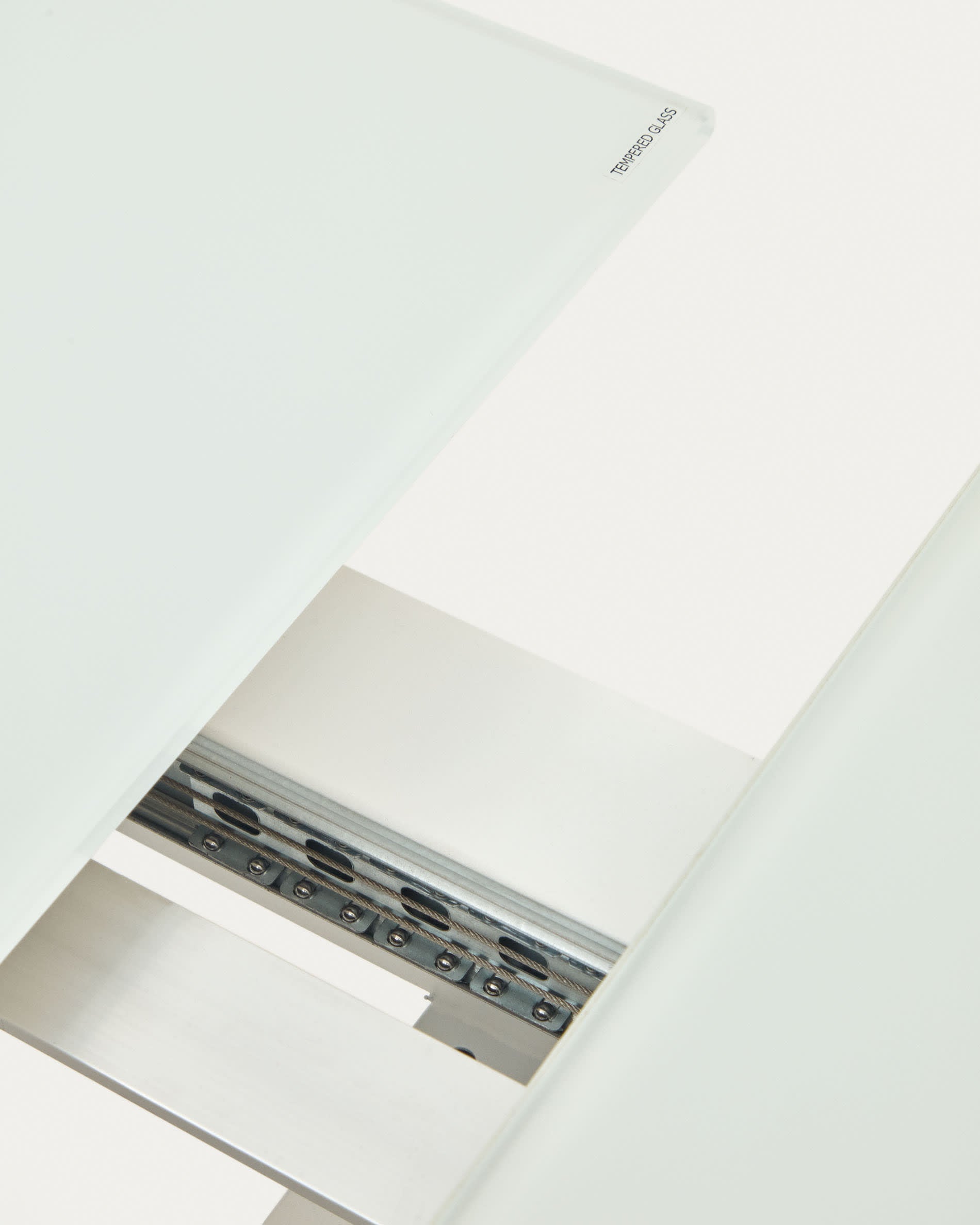 Eleganter Atminda Ausziehtisch mit getempertem Glas und stabilen weißen Stahlbeinen, ideal für flexible Esssituationen und stilvolle Einrichtung.