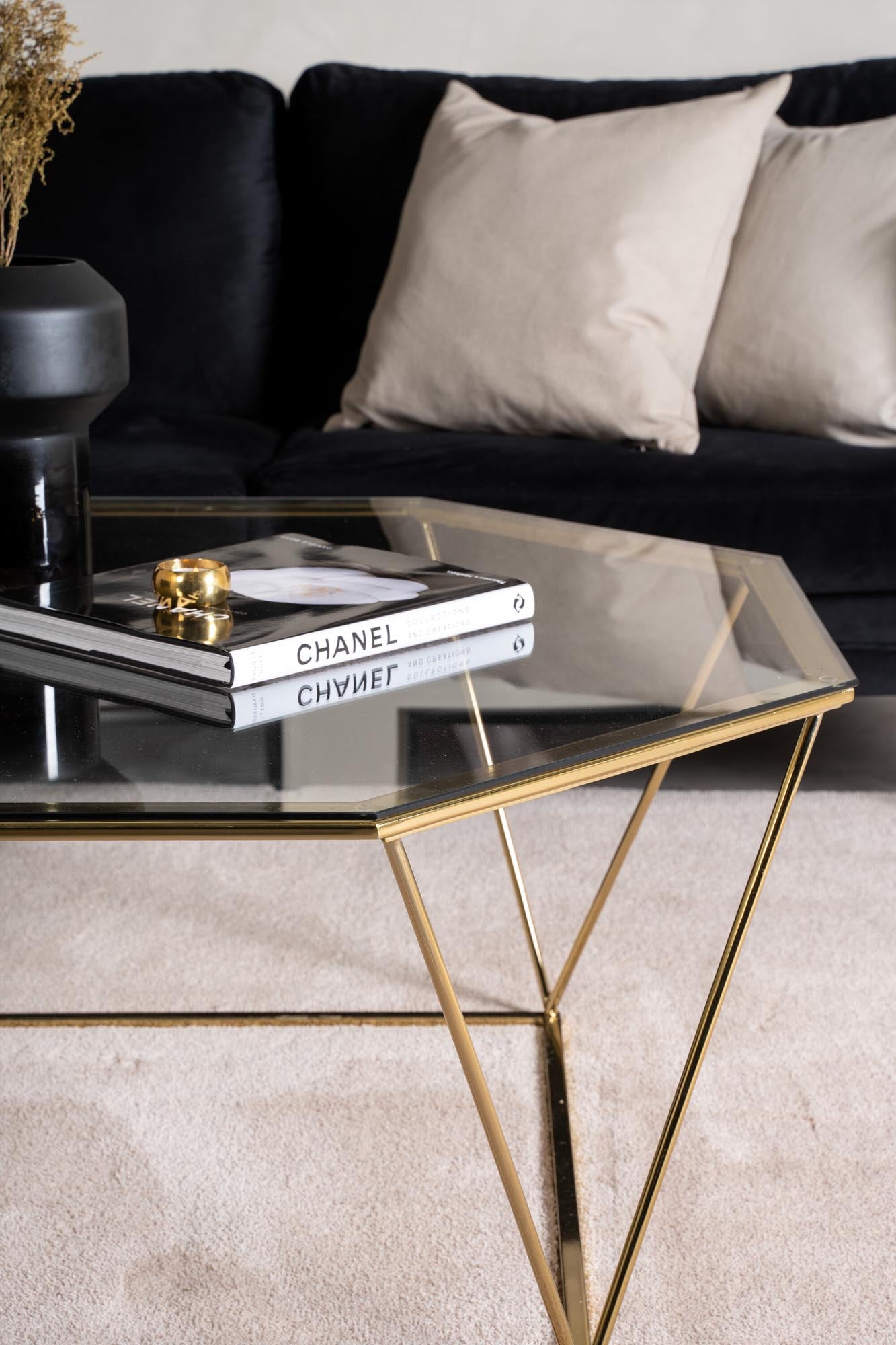 Der Österlen Beistelltisch vereint elegantes achteckiges Design mit einer pflegeleichten Glasplatte und einem stabilen goldenen Stahlrahmen.