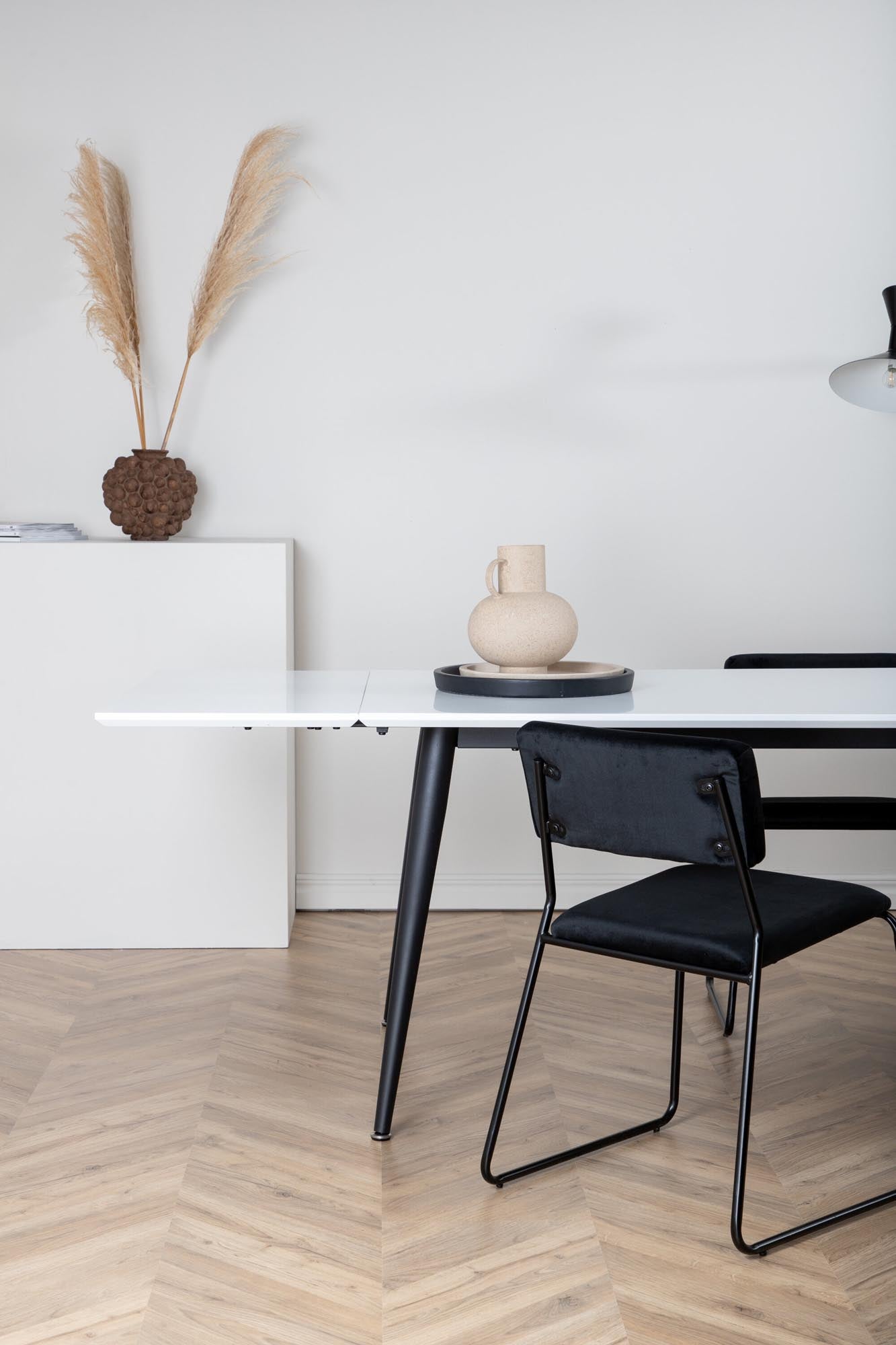 Eleganter Esstisch Jimmy: Weisse HPL-Platte, schwarze Metallbeine, ausziehbar für Flexibilität und Stil.