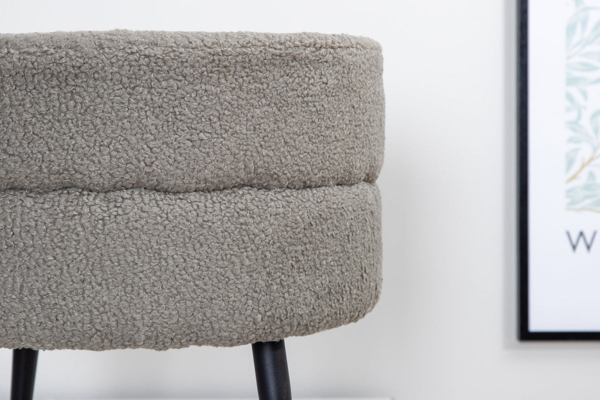 Runder Pouf Pot in Grau mit Teddystoff-Bezug, Durchmesser 40 cm, auf schwarzen, leicht ausgestellten Stahlbeinen stehend.
