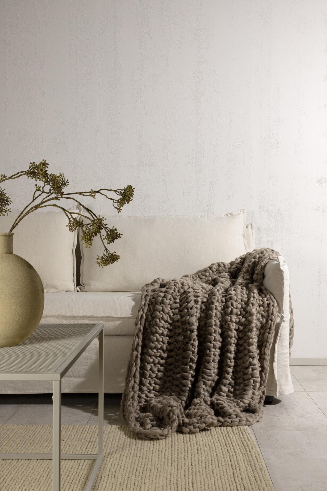 Kuschelige Kate Throw in sanftem Beige, ideal für gemütliche Stunden auf dem Sofa.