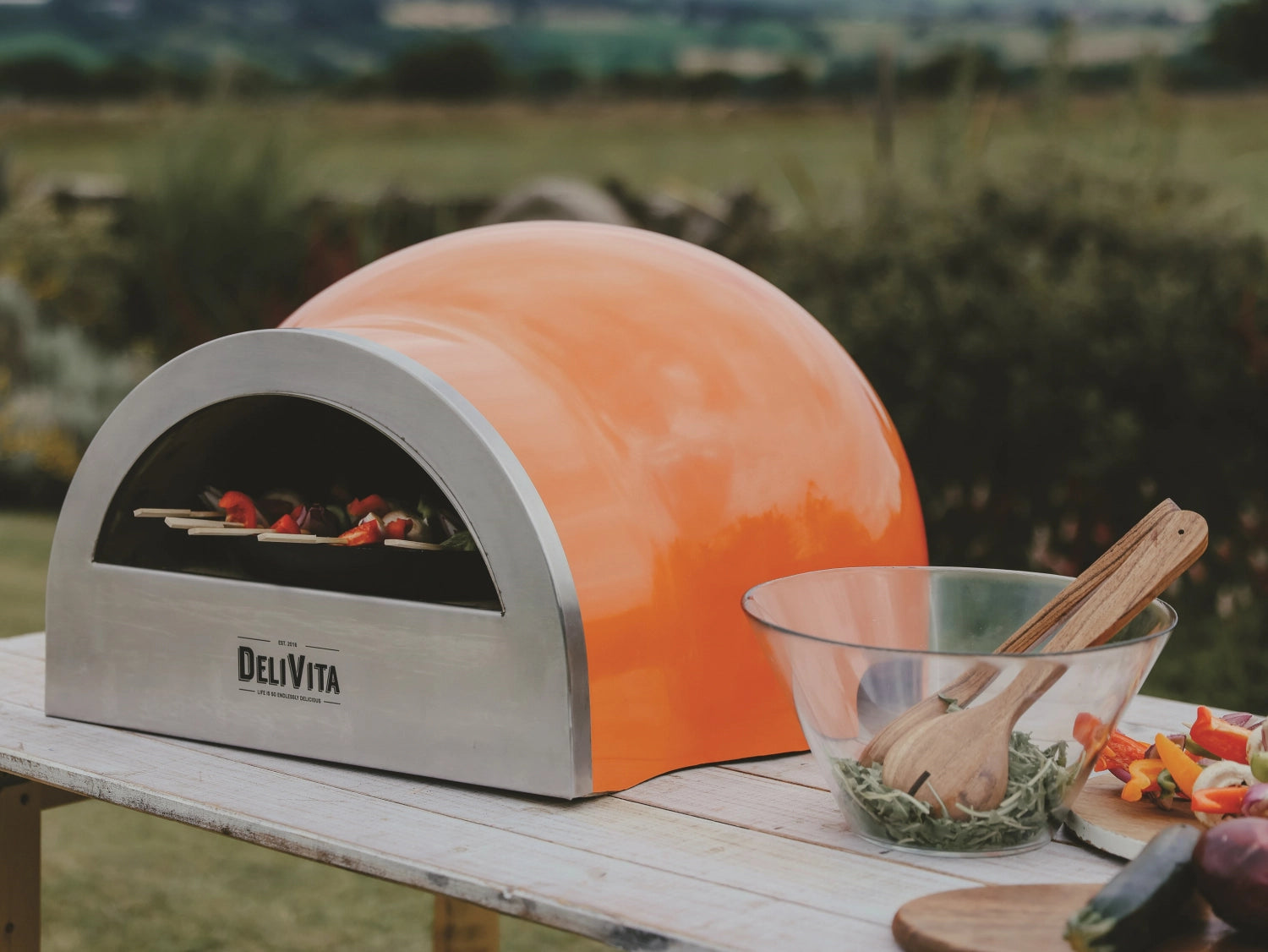 Leuchtend orangefarbener Pizzaofen von Delivita, ideal für die Zubereitung von köstlicher Pizza im Freien, stilvolles Design und hohe Leistung.