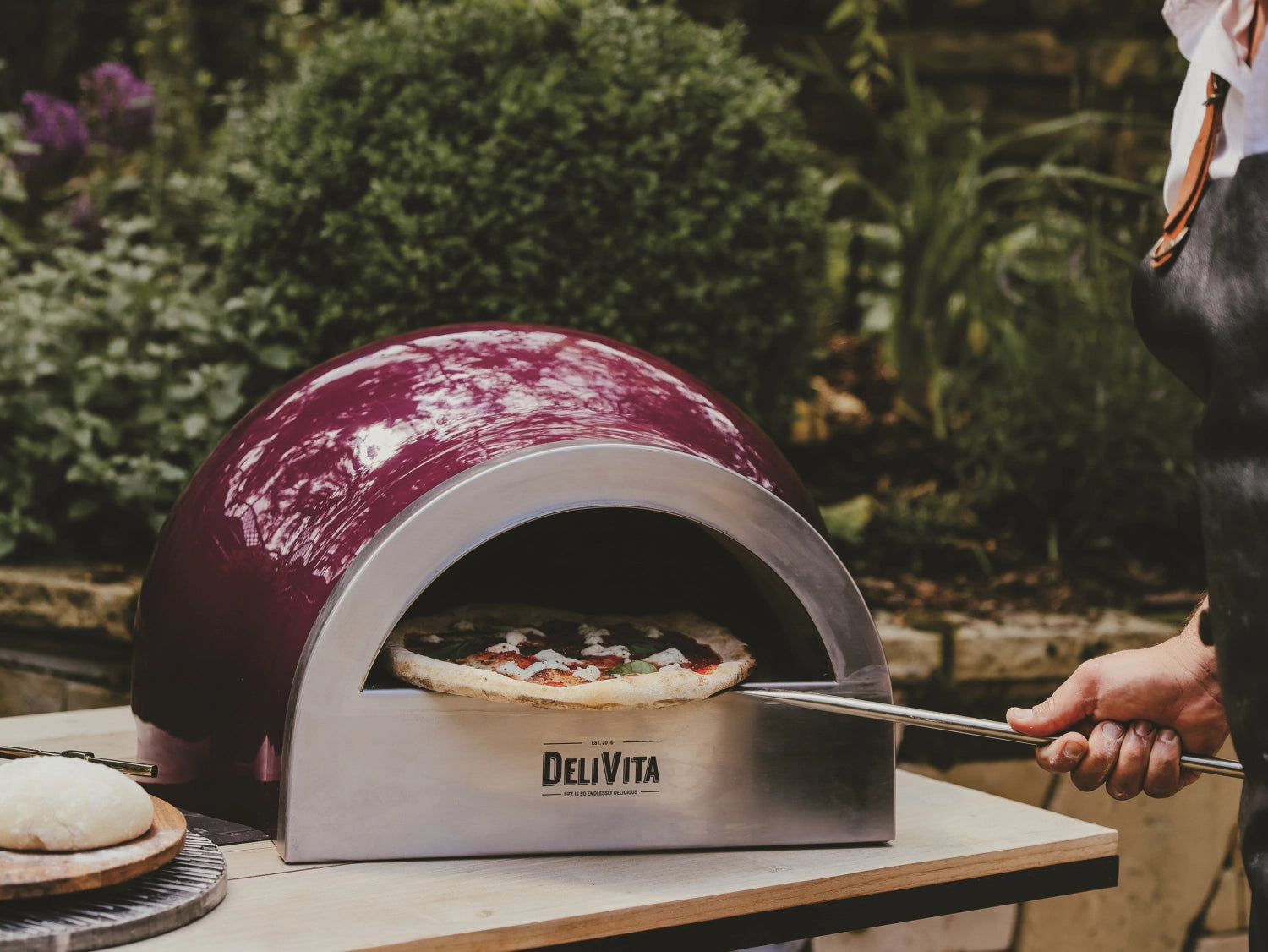Eleganter beerenroter Pizzaofen von Delivita, perfekt für Outdoor-Pizza-Genuss, vereint modernes Design mit hervorragender Leistung.