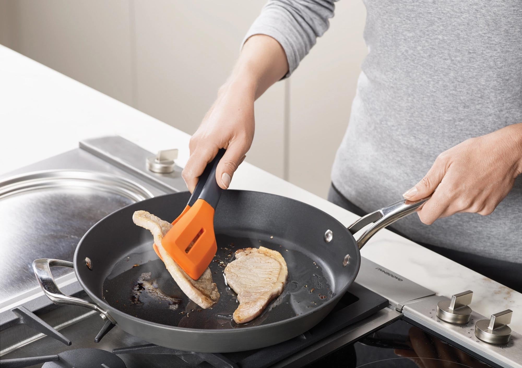Praktische Wender Zange in modernem Grau-Orange, ideal zum Wenden von Speisen. Hitzebeständig, ergonomisch und spülmaschinenfest.