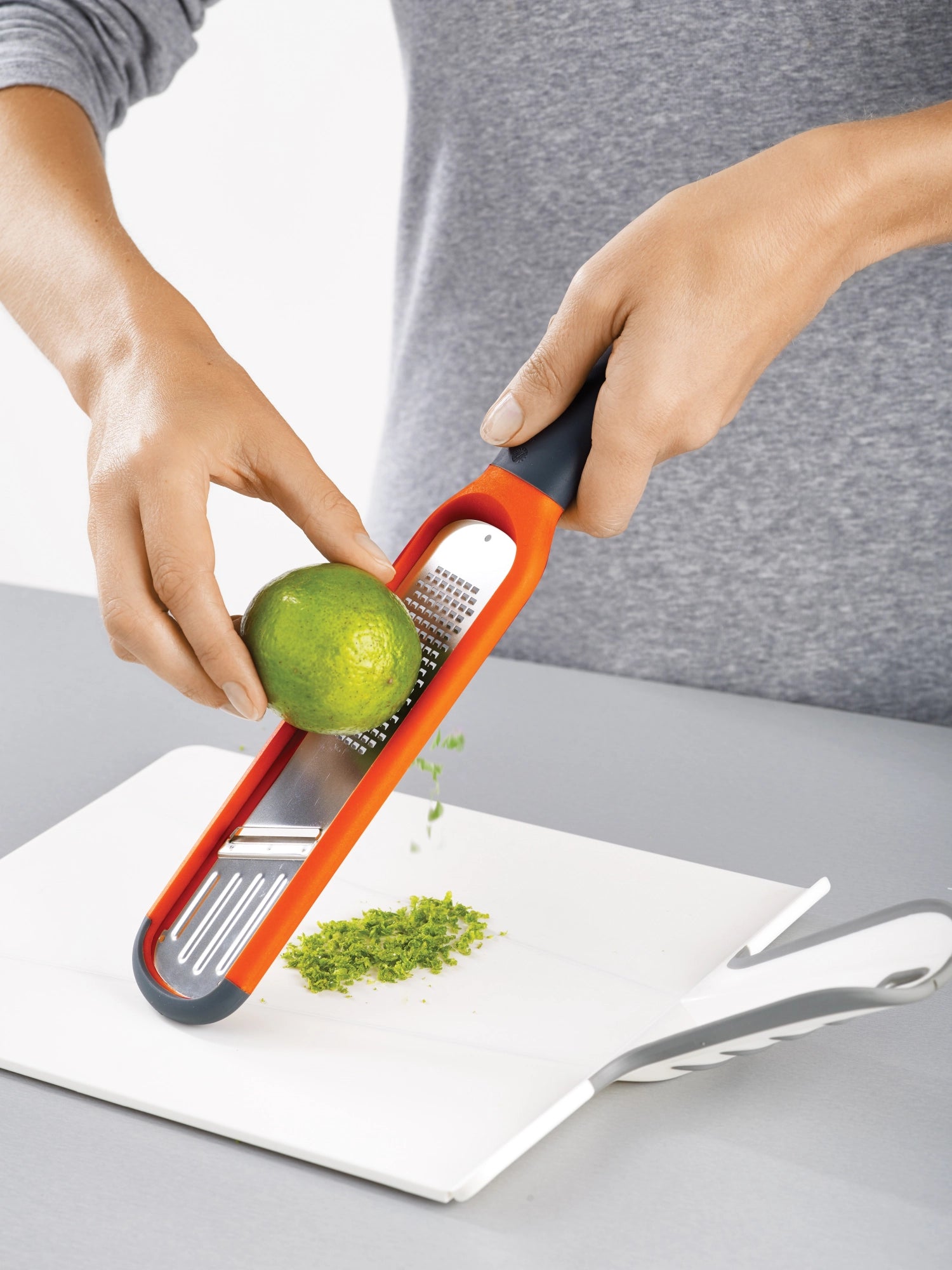 Kompakte Handi-Grate 2-in-1 Mini Reibe in strahlendem Orange, ideal zum Reiben und Raffeln, Maße: 28,5 x 5,7 x 4,3 cm.