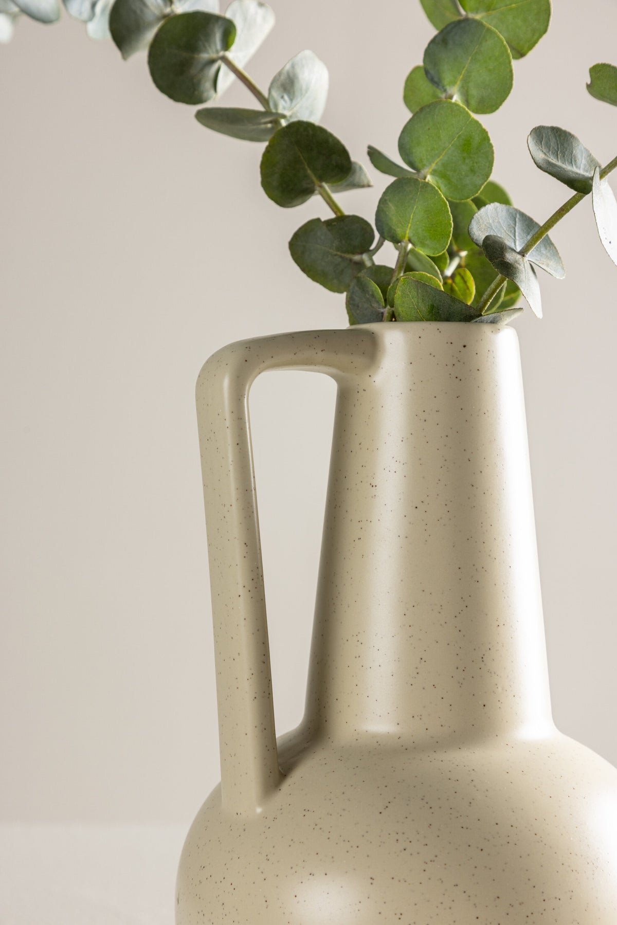 Zylindrische Vase aus Steinzeug in Beige und Schwarz mit seitlichem Griff, matte Oberfläche, Höhe 22 cm, Durchmesser 10 cm.