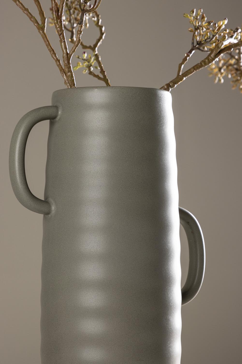 Beige Cent Vase von Venture Home aus Steinzeug mit wellenförmiger Struktur und zwei asymmetrisch angebrachten Griffen an den Seiten.