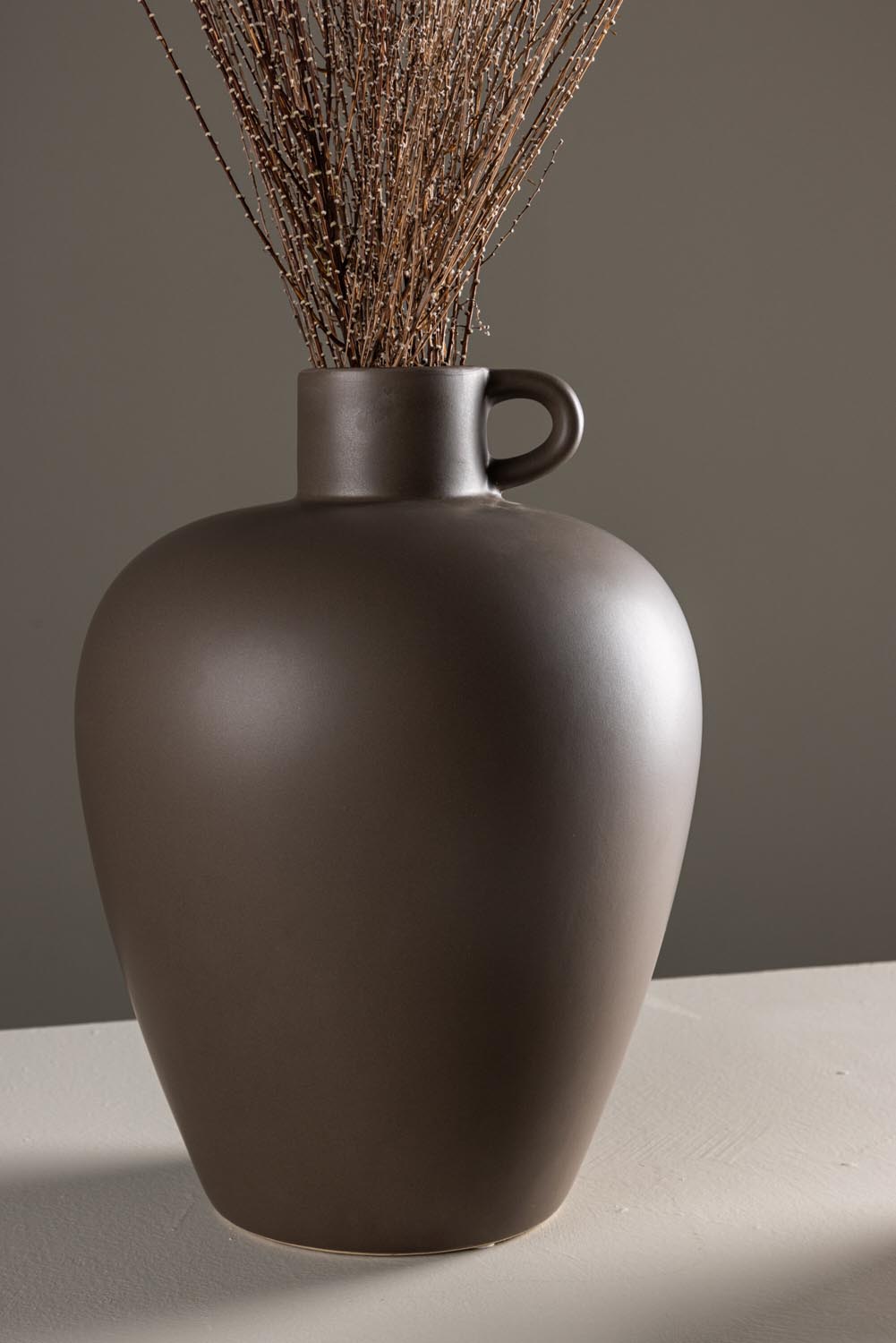Beige Cent Vase von Venture Home aus Steinzeug mit wellenförmiger Struktur und zwei asymmetrisch angebrachten Griffen an den Seiten.
