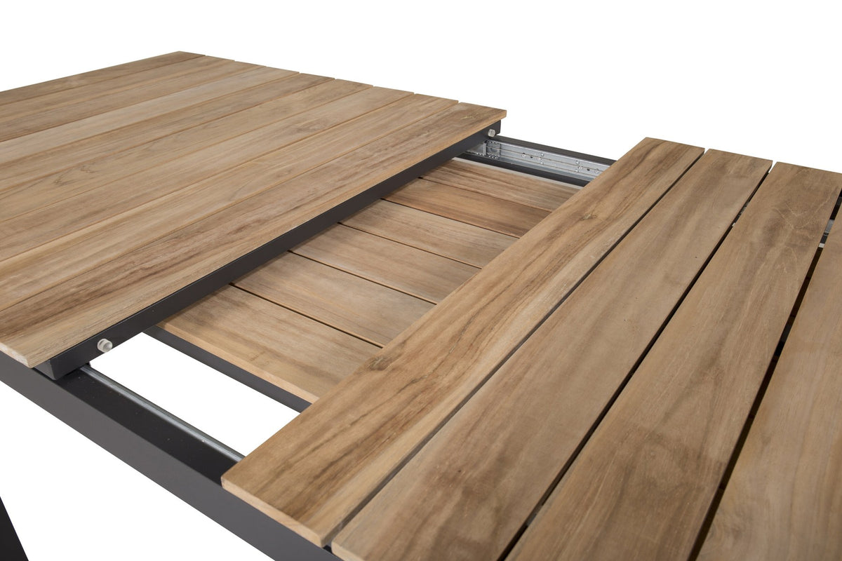 Rechteckiger Gartentisch Mexiko mit naturfarbener Teakholz-Tischplatte und schwarzem Aluminiumgestell, ausziehbar, im Freien aufgestellt.