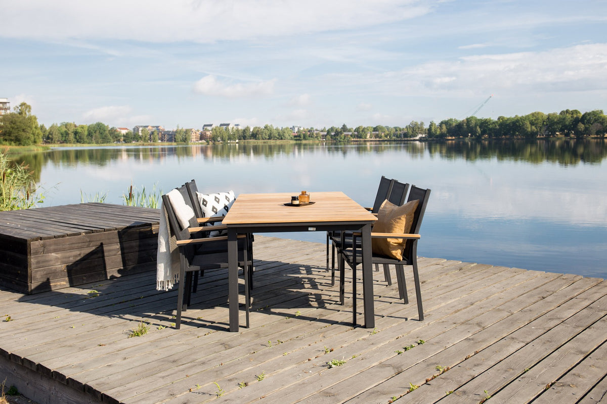 Rechteckiger Gartentisch Mexiko mit naturfarbener Teakholz-Tischplatte und schwarzem Aluminiumgestell, ausziehbar, im Freien aufgestellt.