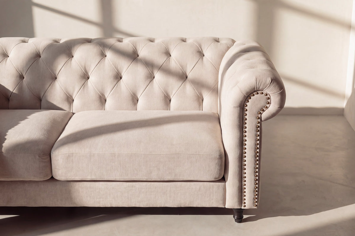 Beiges 3-Sitzer-Sofa Velvet von Venture Home mit Polyester-Samt-Bezug, tiefer Knopfheftung und schwarzen Gummibaumholz-Beinen im Chesterfield-Design.