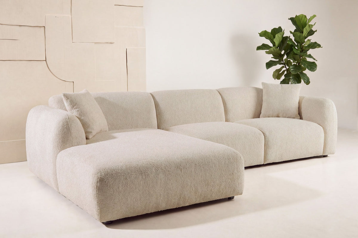 Beiges Chaiselongue-Sofa mit L-Form, Polyester-Bezug, schwarzen Holzbeinen und rechtsseitiger Chaiselongue, freigestellt fotografiert.