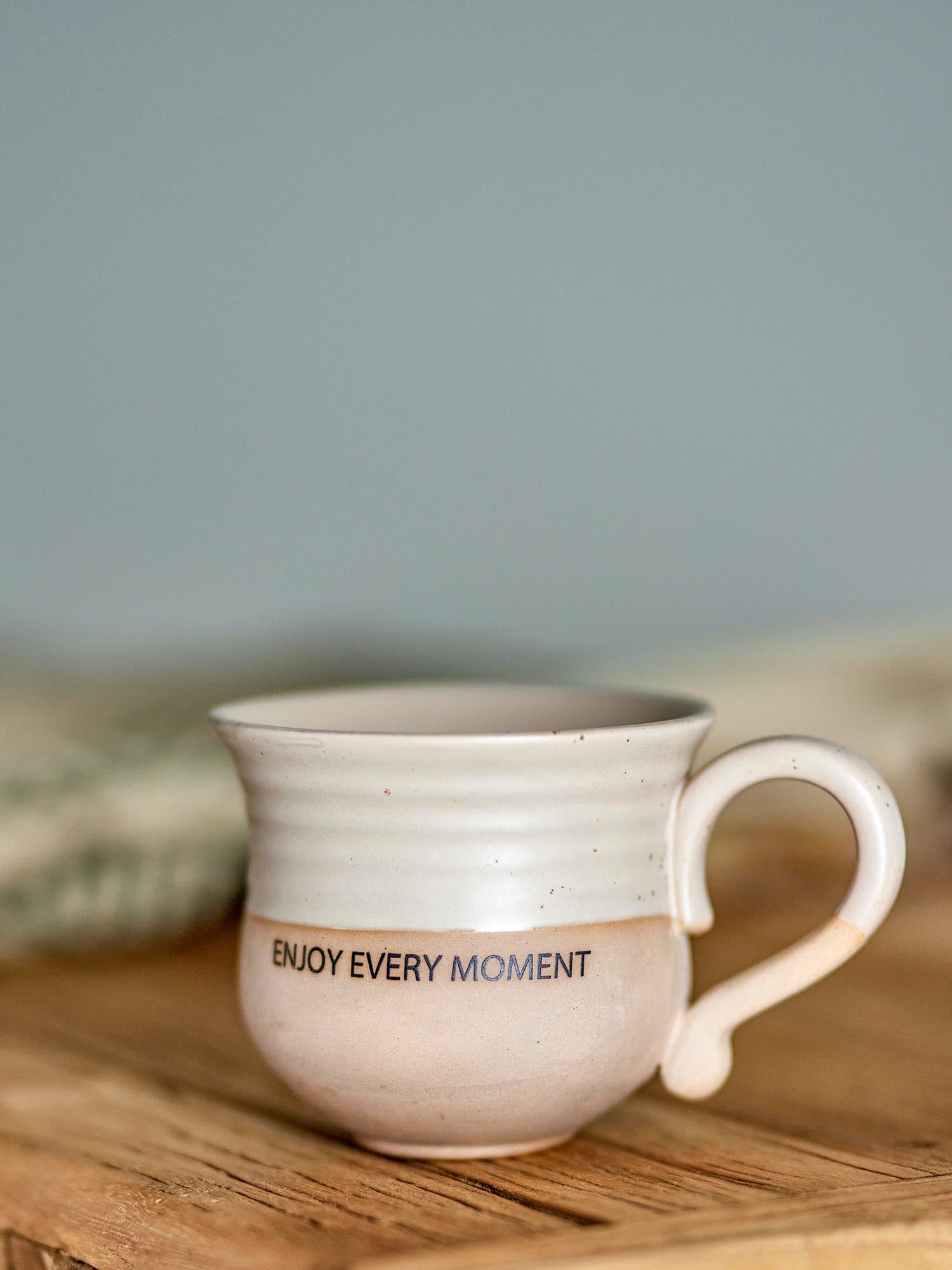Elegante Steingut-Tasse in Braun mit "Geniesse jeden Moment"-Text, ideal für heisse Getränke.
