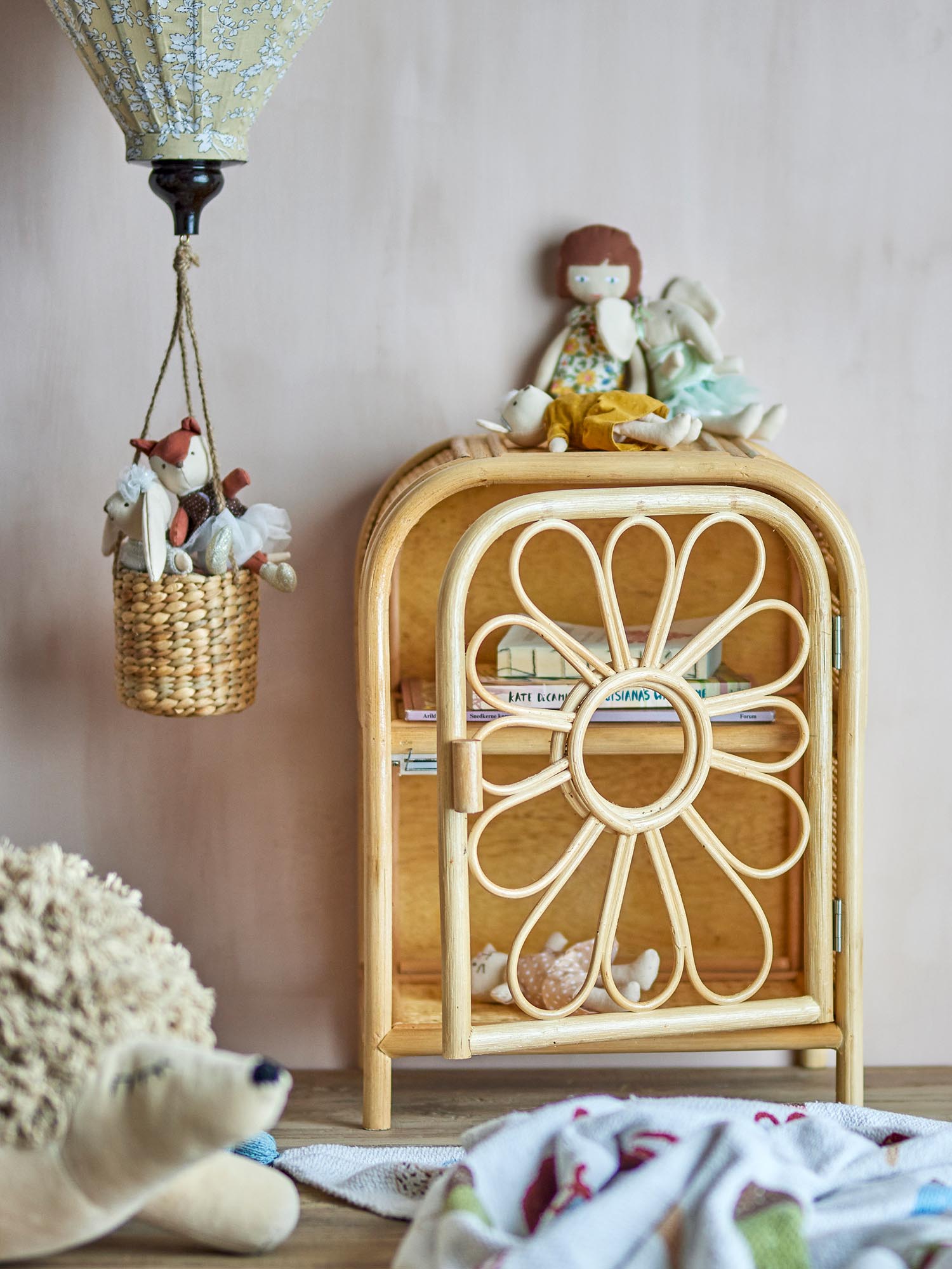 Ein verspieltes Rattan-Kabinett mit blumenförmiger Tür, ideal für Kinderzimmer, bietet stilvolle Aufbewahrung und skandinavischen Charme.