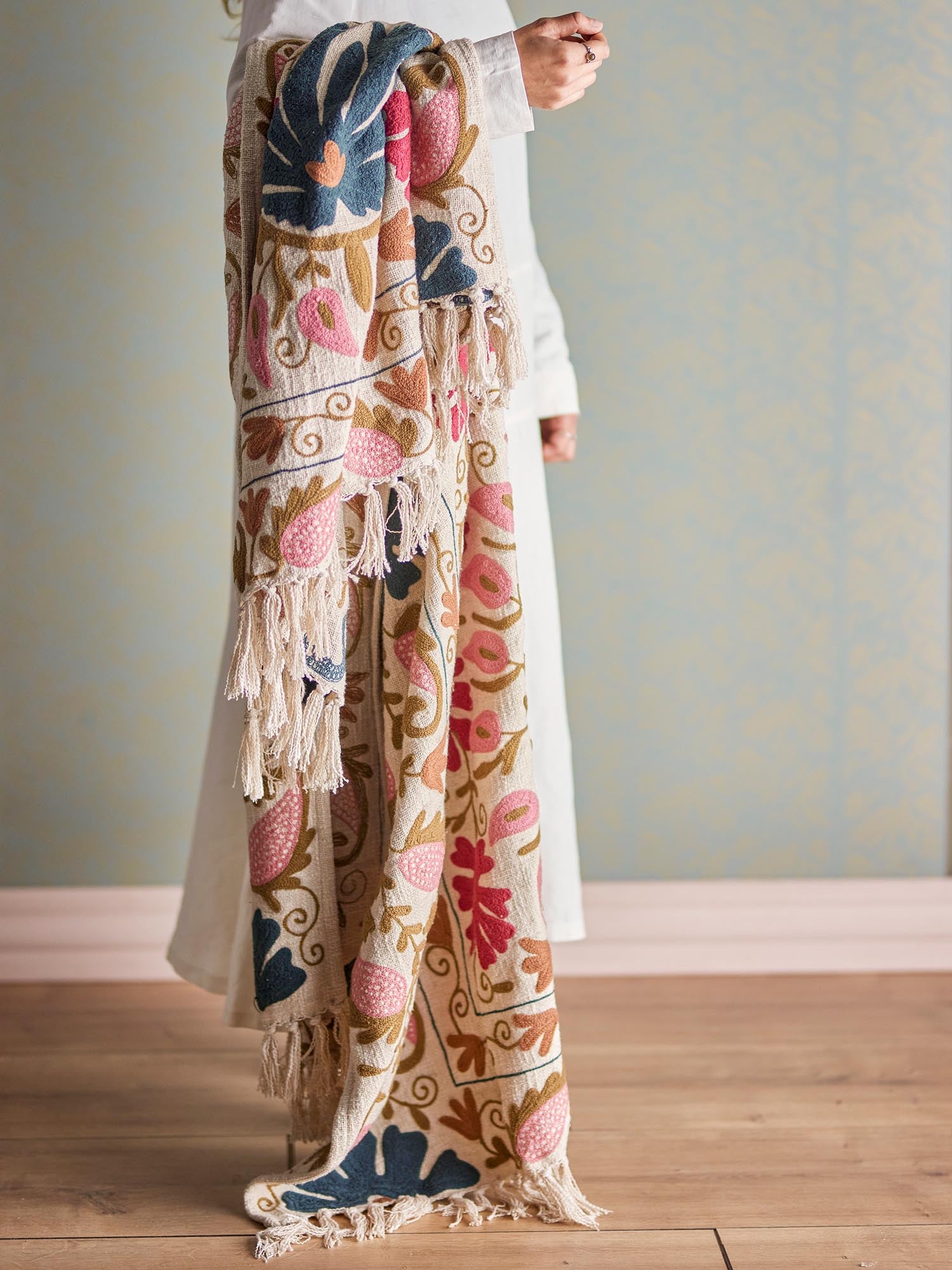 Die Ceva Decke in zartem Rosa vereint skandinavische Eleganz mit weicher Baumwolle und kunstvollem Stickdesign.