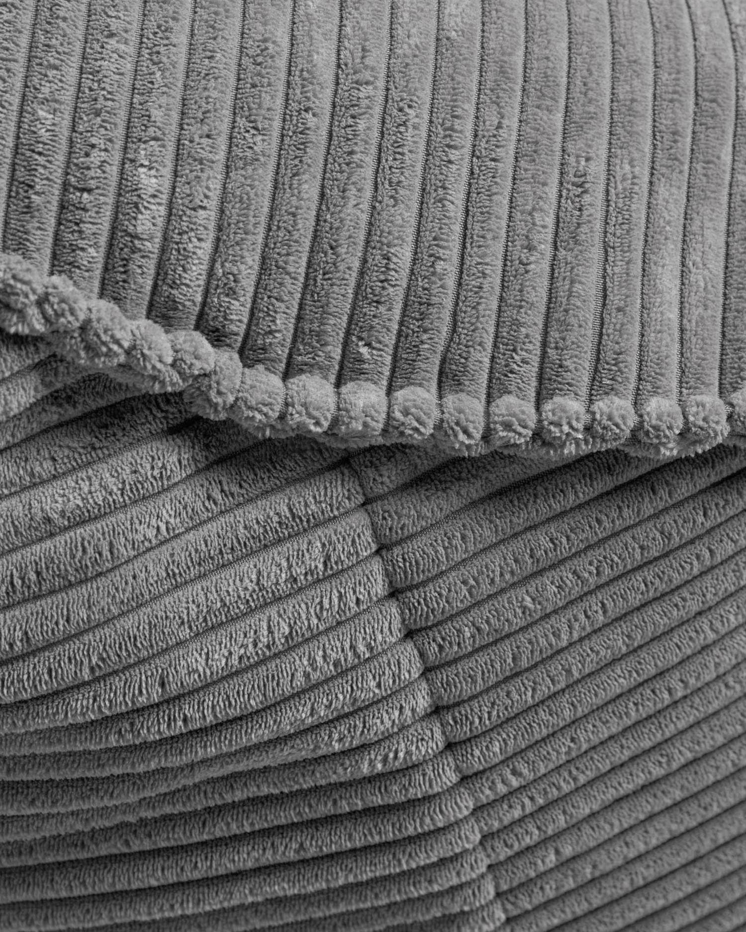 Der Wilma Pouf aus breitem grauem Cord (Ø 80 cm) ist ein elegantes und vielseitiges Wohnaccessoire, das jedem Raum eine gemütliche Note verleiht.