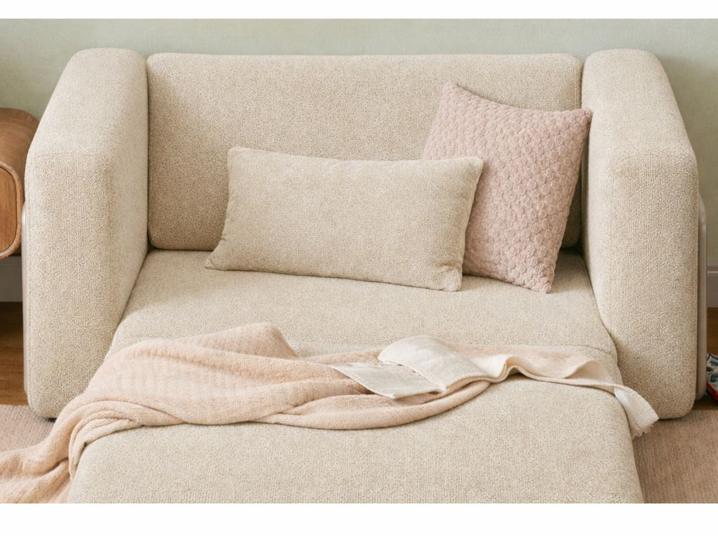 Cremefarbenes 1-Sitzer Schlafsofa Wello aus Bouclé-Stoff mit kompakter Sitzfläche und ausklappbarer Liegefläche im Wohnraum.