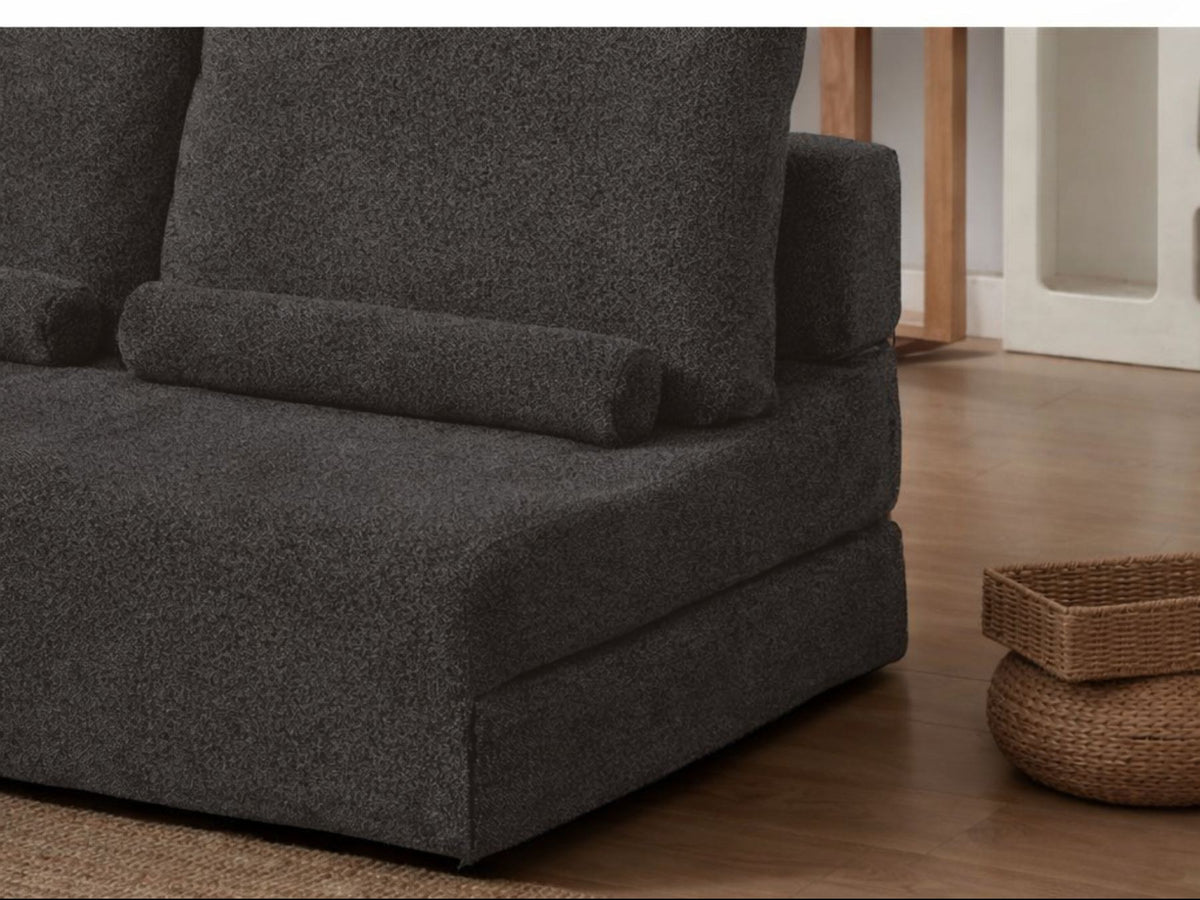 Anthrazitfarbenes 2-Sitzer Schlafsofa Wello aus Bouclé-Stoff mit kompakter Form, Armlehnen und flacher Sitzfläche, aufgestellt im Wohnraum.