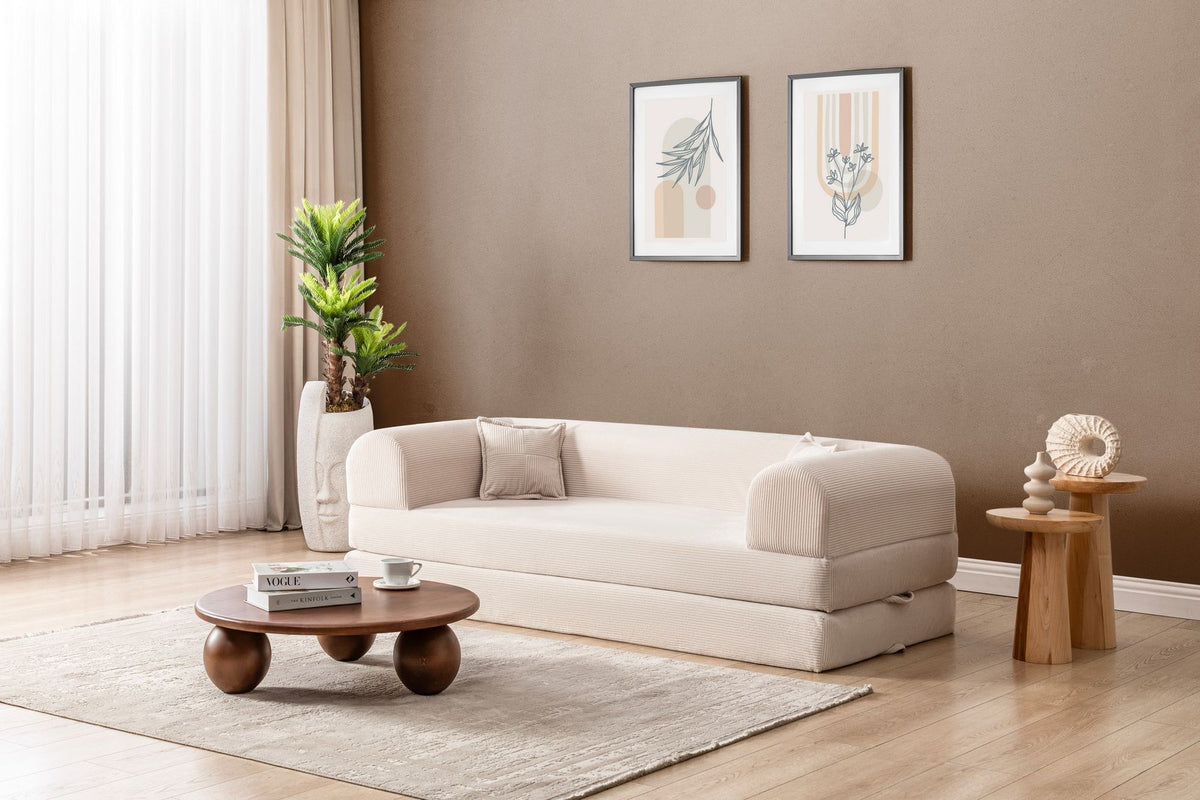 Cremefarbenes 3-Sitzer Schlafsofa Legom Eco von Hanah Home aus geripptem Cord-Plüschstoff mit zwei Kissen im Roll-Pack-Design abgebildet.
