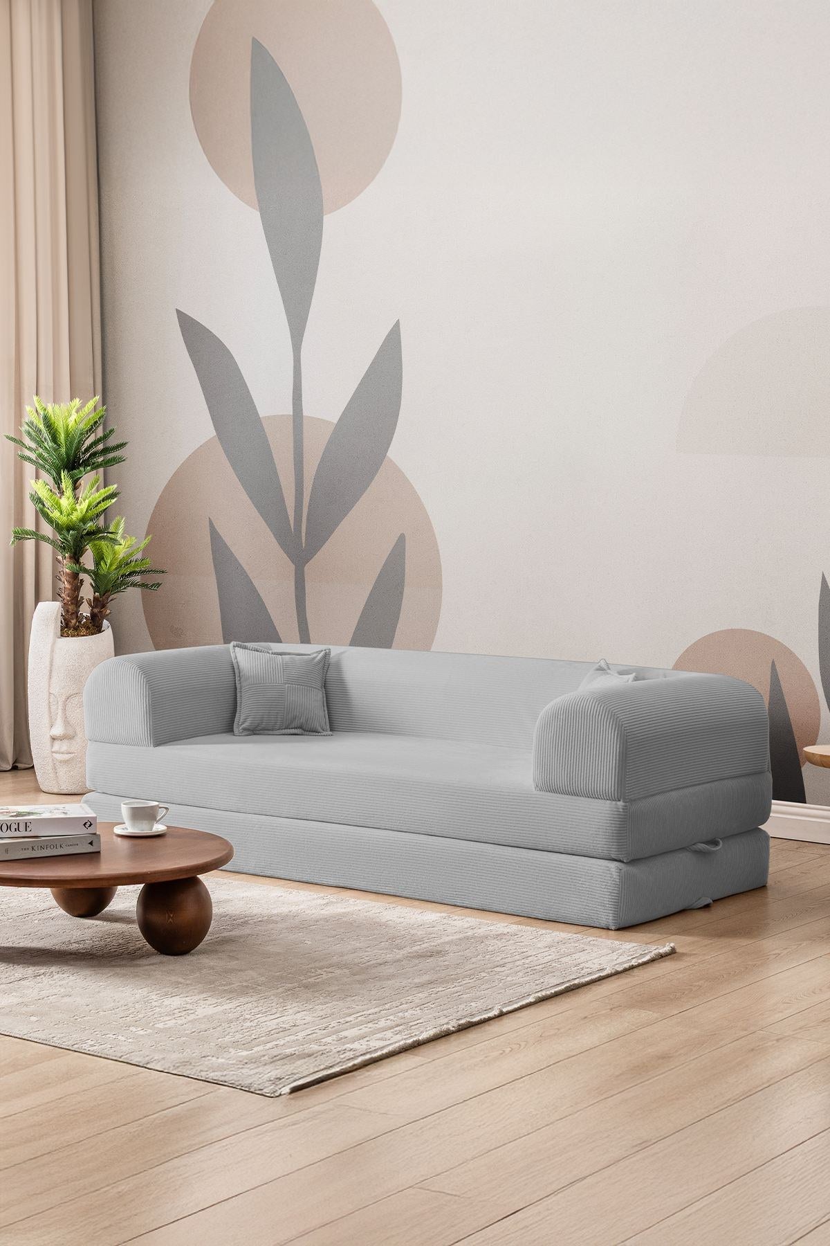 Hellgraues 3-Sitzer Schlafsofa aus geripptem Cord-Plüschstoff mit zwei Kissen, Rollpack-Design und rutschfester Sohle.
