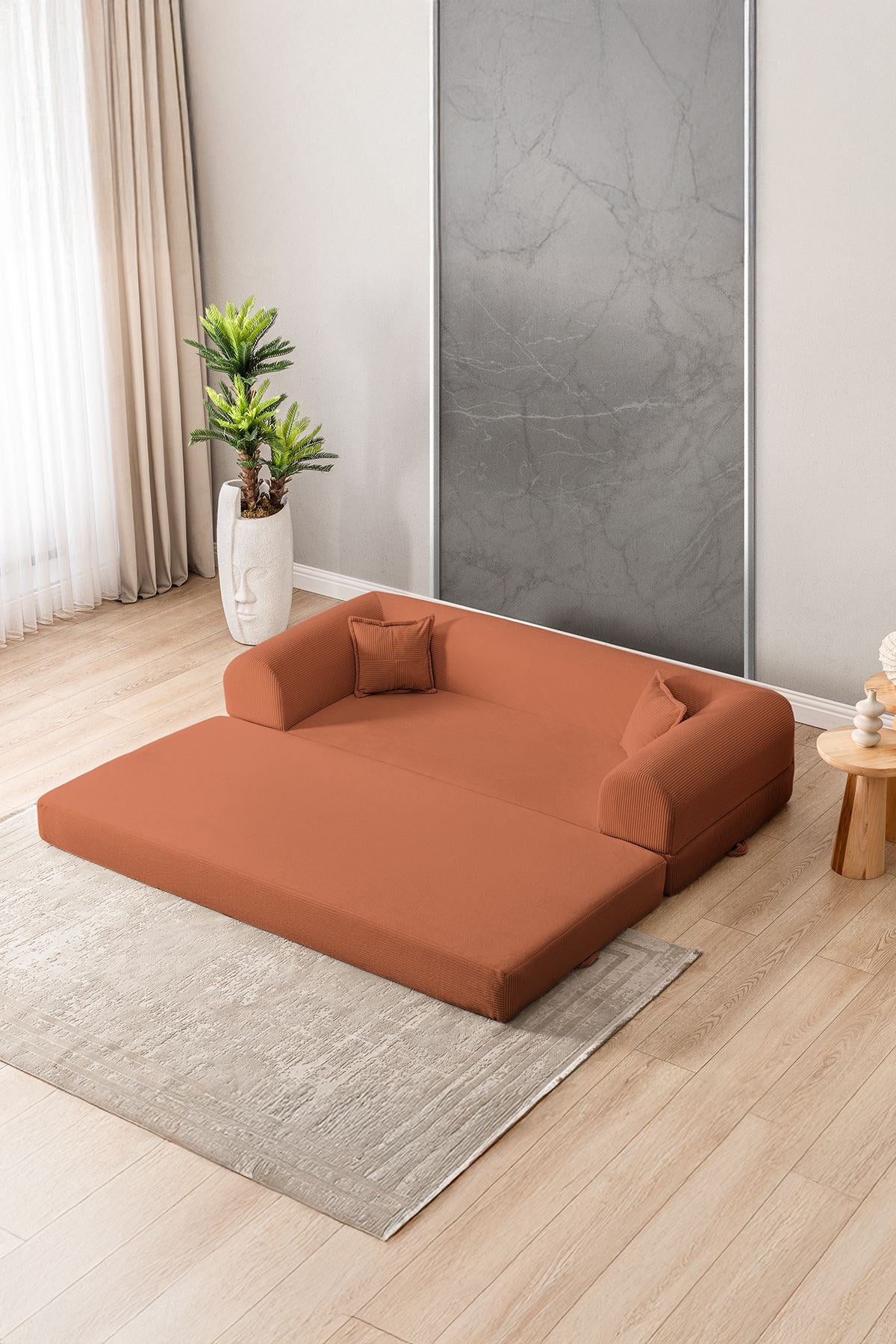 Orangefarbenes 3-Sitzer Schlafsofa aus geripptem Plüschstoff mit zwei Kissen, Rollpack-Design und rutschfester Sohle, Frontalansicht.