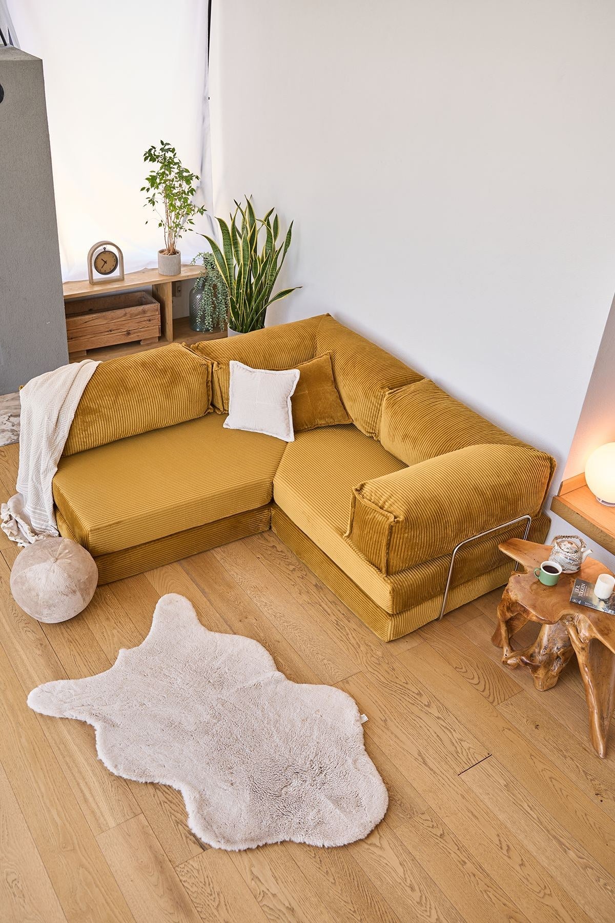 Senfgelbes Eck-Schlafsofa Kanyon von Hanah Home aus geripptem Cord-Plüschstoff mit vier Kissen und rutschfester Sohle.