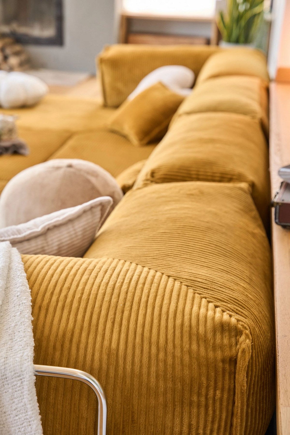 Senfgelbes Eck-Schlafsofa Kanyon von Hanah Home aus geripptem Cord-Plüschstoff mit vier Kissen und rutschfester Sohle.