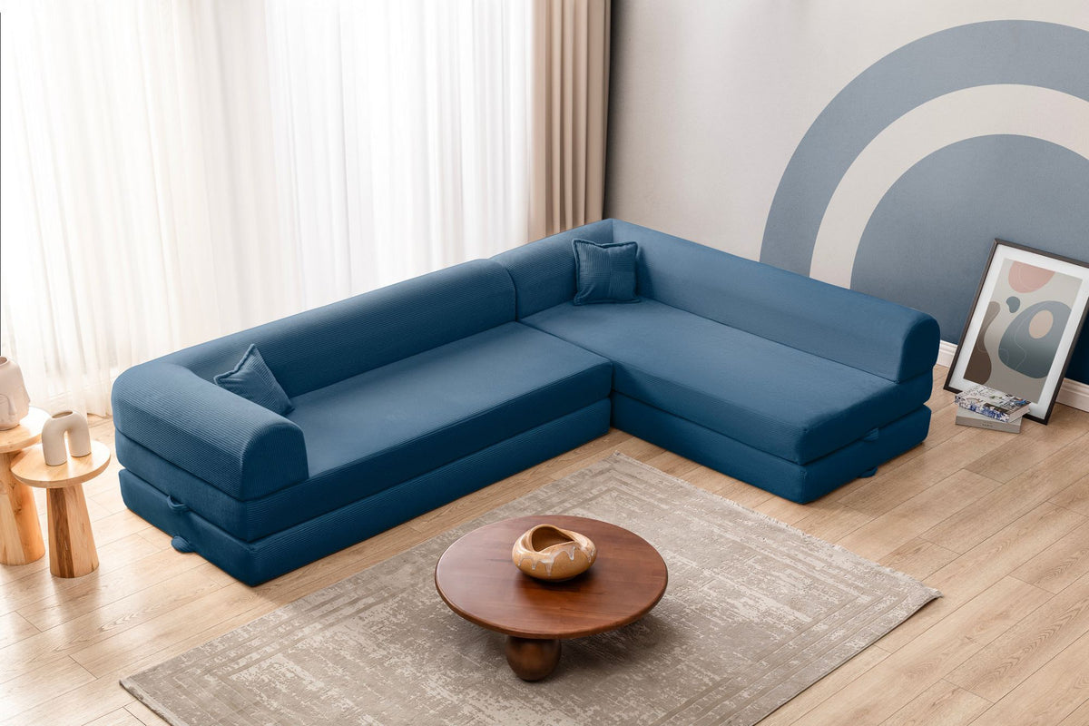 Blaues Ecksofa-Bett aus geripptem Cord-Plüschstoff mit vier Kissen, abnehmbarem Bezug und rutschfester Sohle, Frontalansicht.
