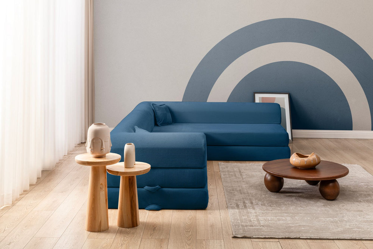 Blaues Ecksofa-Bett aus geripptem Cord-Plüschstoff mit vier Kissen, abnehmbarem Bezug und rutschfester Sohle, Frontalansicht.
