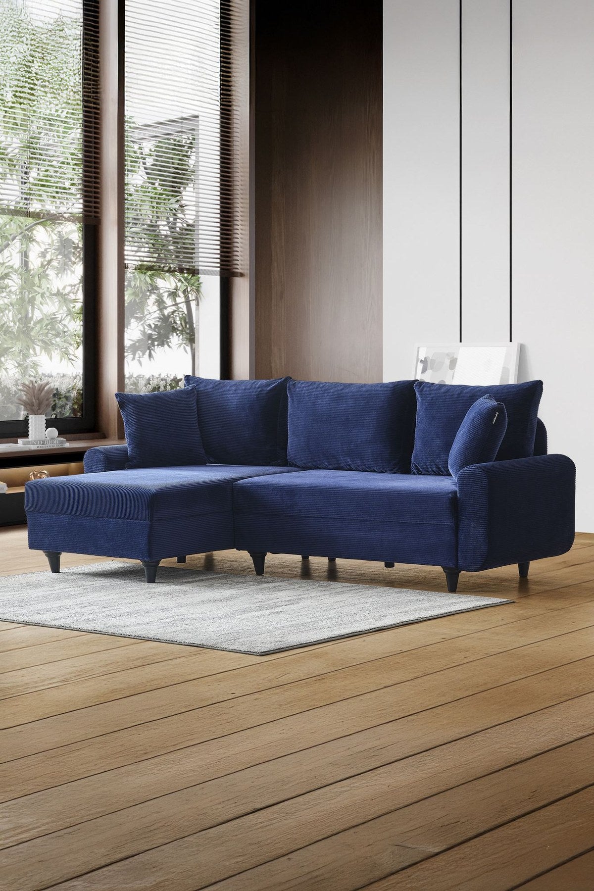 Marineblaues Ecksofa Flavia von Hanah Home mit Metallgestell, Polyesterbezug in Leinenstruktur und Kunststoffbeinen im Wohnraum.