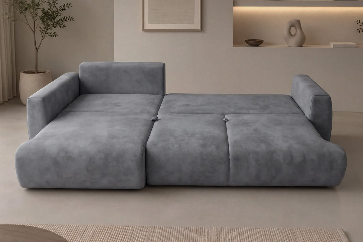Graues Ecksofa Arthur mit Schlaffunktion, Gestell aus Buchenholz und Spanplatte, Bezug aus Polyester, Kunststoffbeine, zwei Kissen sichtbar.