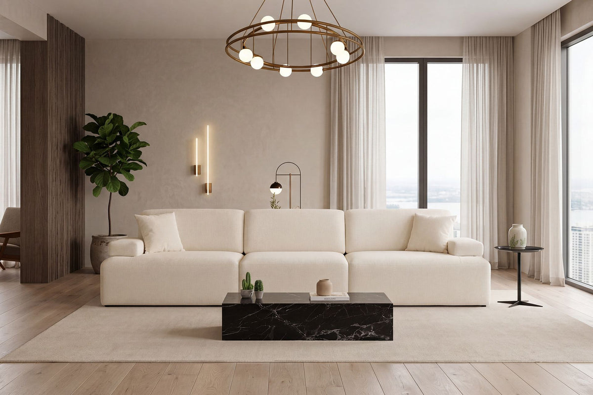 Cremefarbenes Madlen 4-Sitzer Sofa von Hanah Home mit niedrigen Kunststoffbeinen, Polyesterbezug und zwei Kissen auf hellem Untergrund.