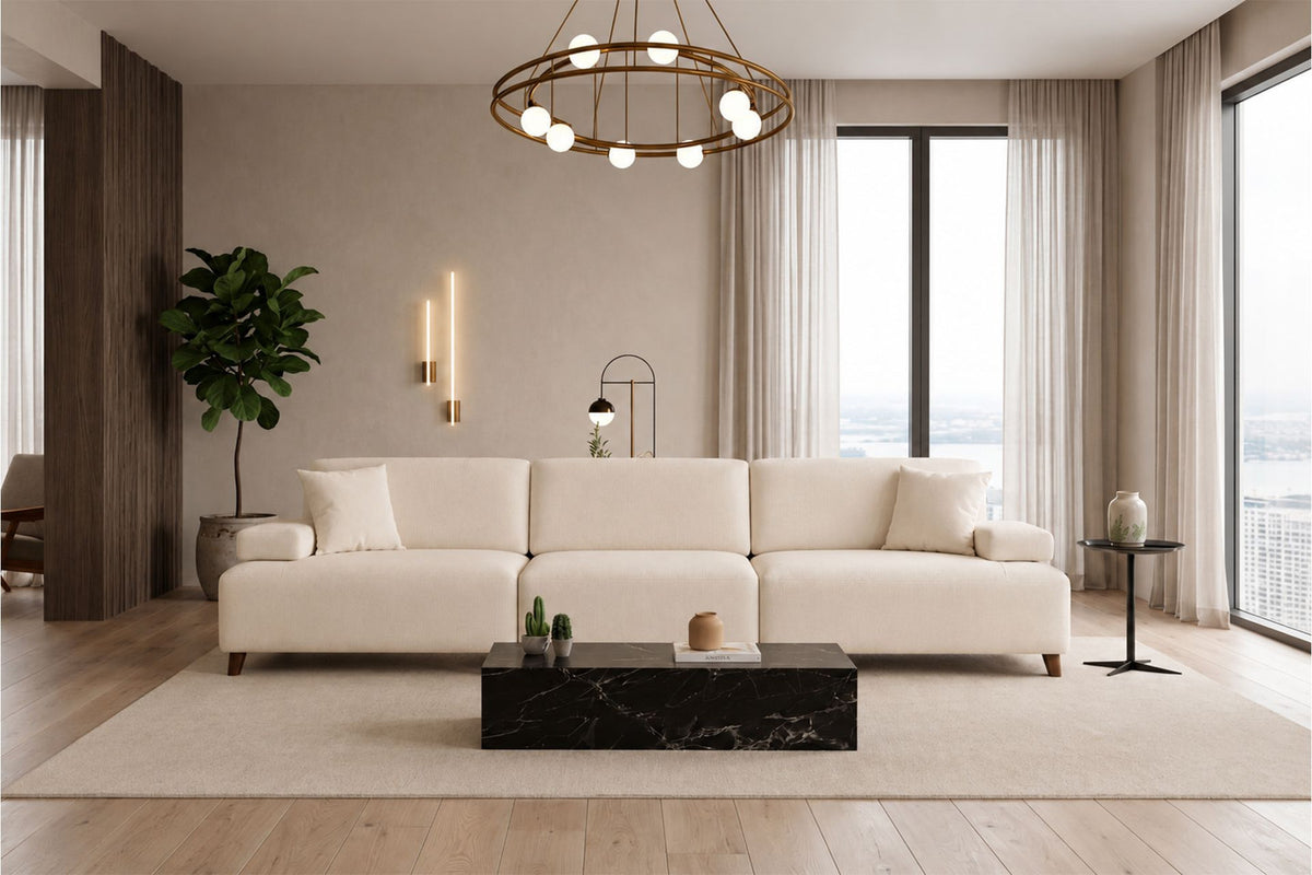 Cremefarbenes 4-Sitzer-Sofa mit hohen Kunststoffbeinen, Polyesterbezug, Buchenholzgestell und zwei losen Kissen auf hellem Hintergrund.