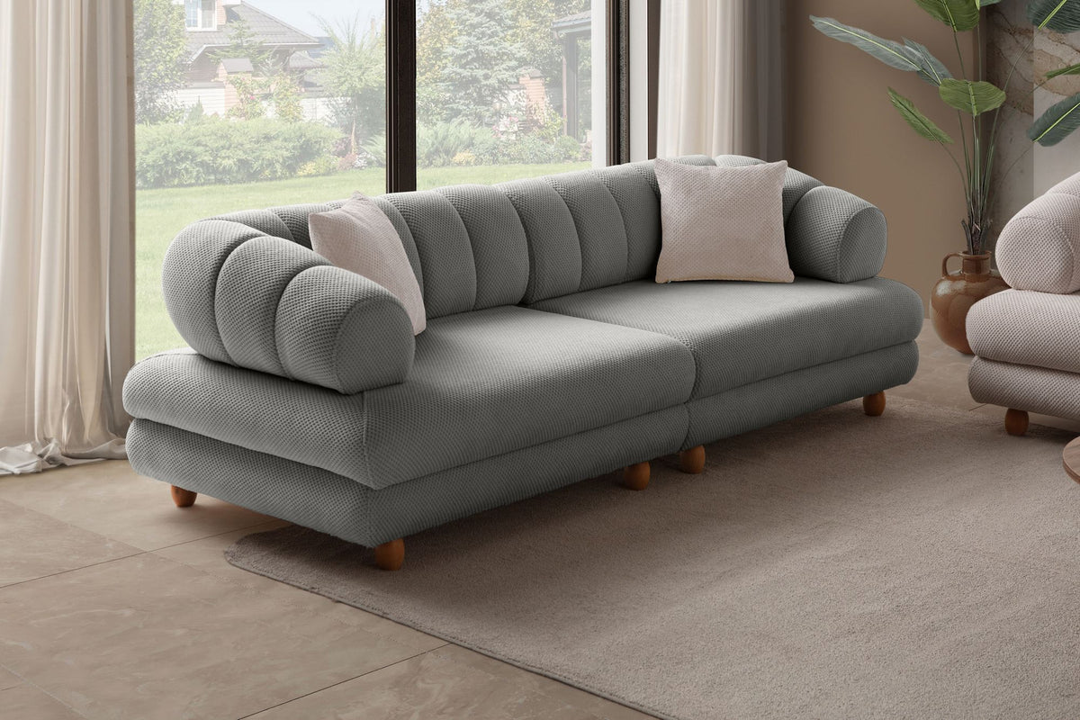 Graues 3-Sitzer Sofa Gloria von Hanah Home mit Polyesterbezug in Tuna-Struktur, Holzbeinen und zwei losen Kissen auf hellem Untergrund.