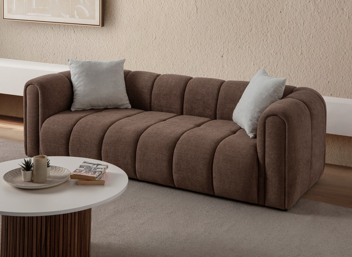 Braunes 3-Sitzer Sofa mit Boucle-Bezug, Hainbuche-Gestell, Kunststoffbeinen und zwei losen Kissen, fotografiert im Wohnraum.