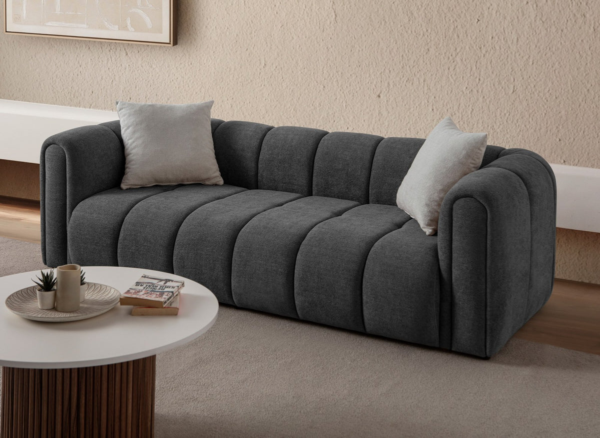 Anthrazitfarbenes 3-Sitzer Sofa N-Line von Hanah Home mit Boucle-Stoffbezug, Kunststoffbeinen und zwei Kissen.