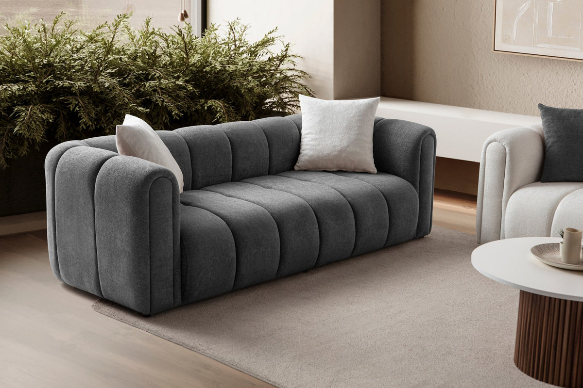 Anthrazitfarbenes 3-Sitzer Sofa N-Line von Hanah Home mit Boucle-Stoffbezug, Kunststoffbeinen und zwei Kissen.