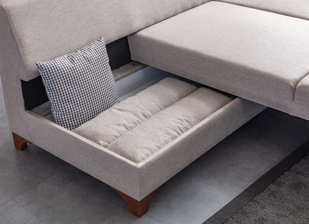 Cremefarbenes Eckschlafsofa T-Loft von Hanah Home mit Leinenstruktur-Stoffbezug, Kunststoffbeinen und acht dekorativen Kissen.