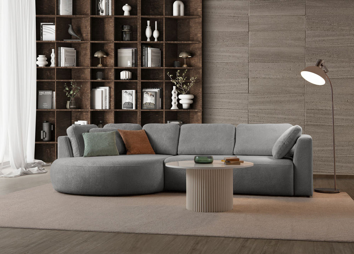 Graues Ecksofa Venezia links von Hanah Home mit Polyesterbezug, Hainbuche-Gestell, Kunststoffbeinen und neun Kissen im Wohnraum.