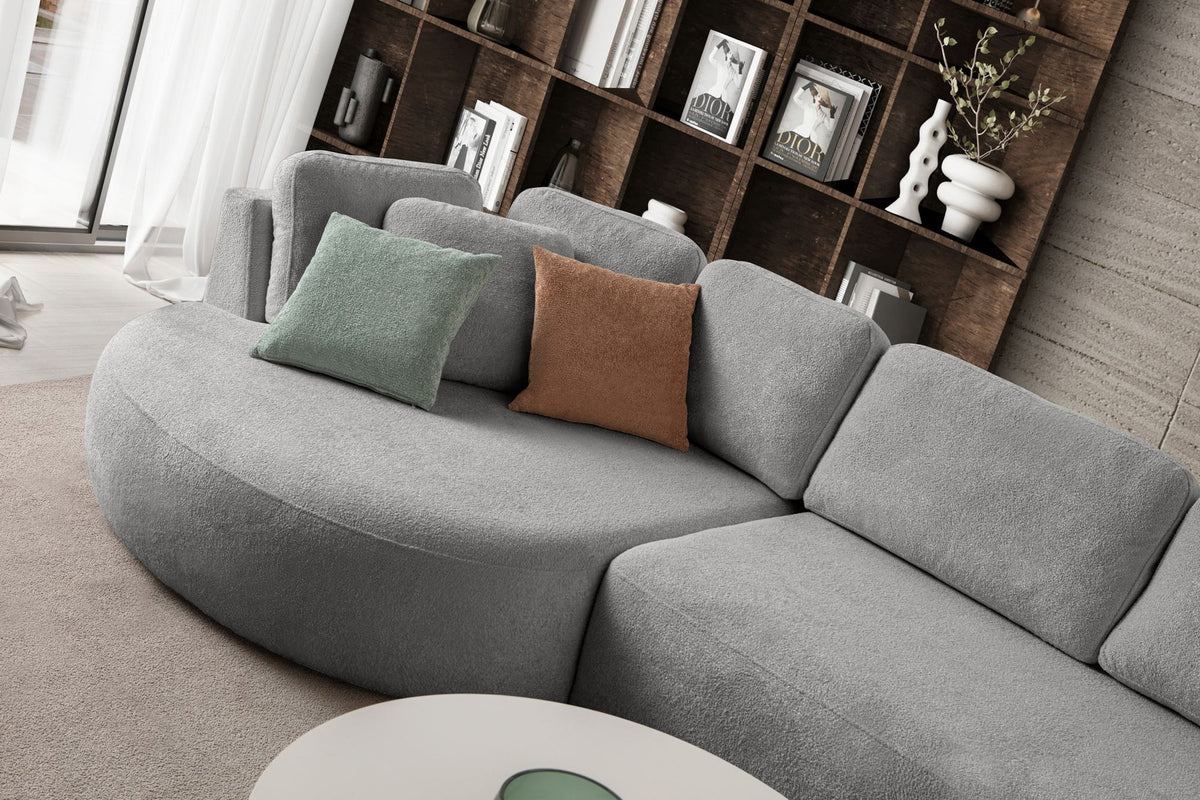 Graues Ecksofa Venezia links von Hanah Home mit Polyesterbezug, Hainbuche-Gestell, Kunststoffbeinen und neun Kissen im Wohnraum.