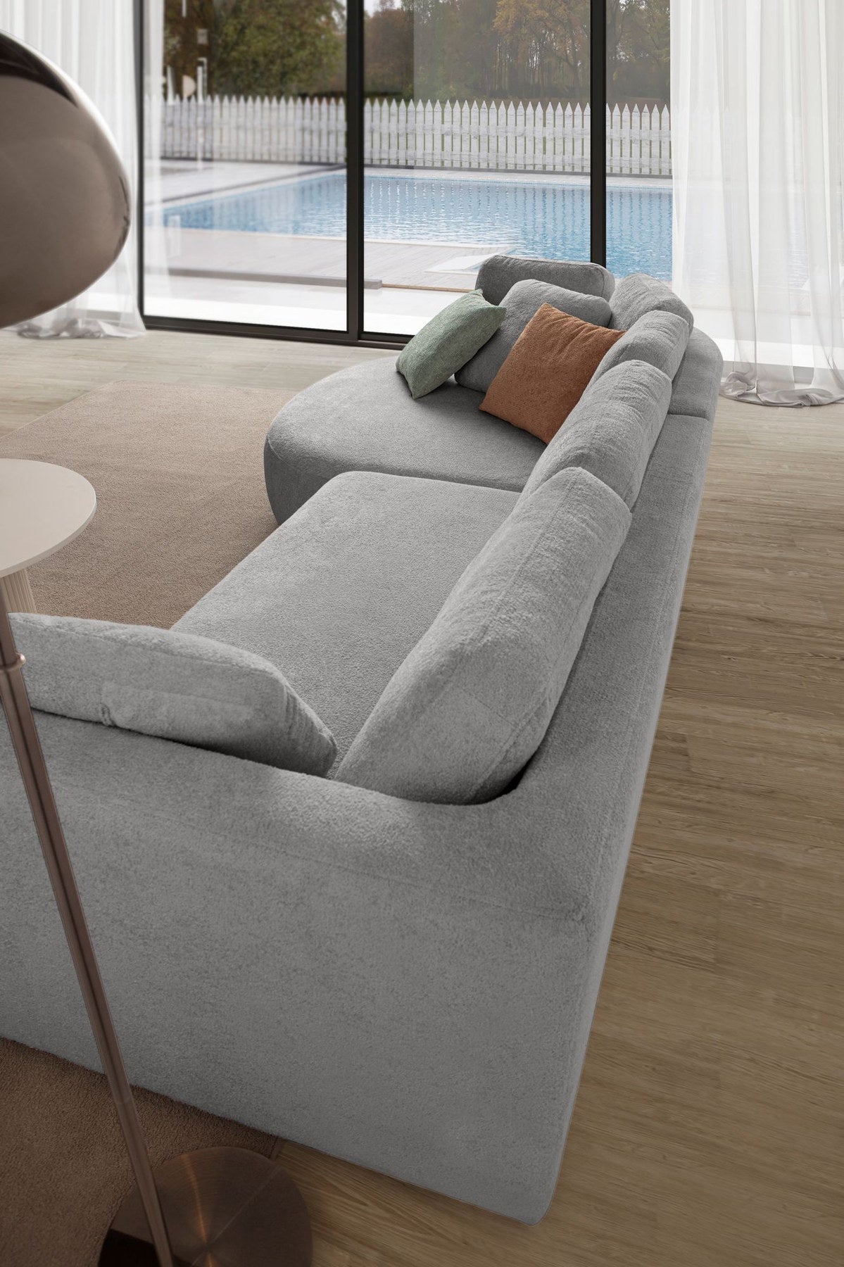 Graues Ecksofa Venezia links von Hanah Home mit Polyesterbezug, Hainbuche-Gestell, Kunststoffbeinen und neun Kissen im Wohnraum.