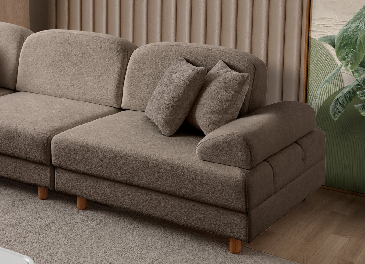 Braunes Eck-Schlafsofa Aries Modular M mit Coco-Boucle-Stoffbezug, Holzbeinen und sichtbarer Truhe, im Wohnzimmer aufgestellt.