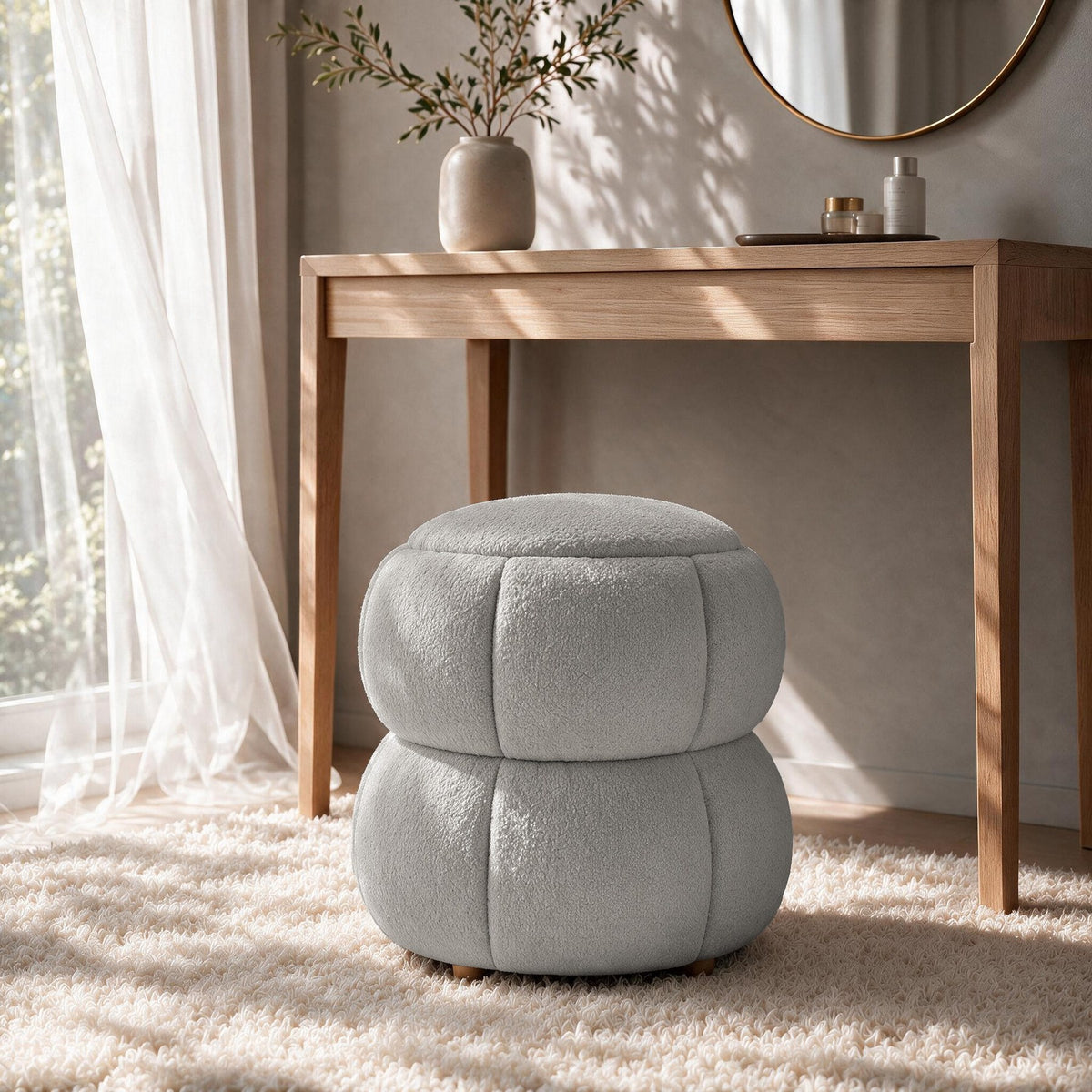 Runder Pouf in Hellgrau mit gestricktem Polyesterbezug, Holzkugelfüssen und gepolstertem Sitzbereich auf hellem Hintergrund fotografiert.