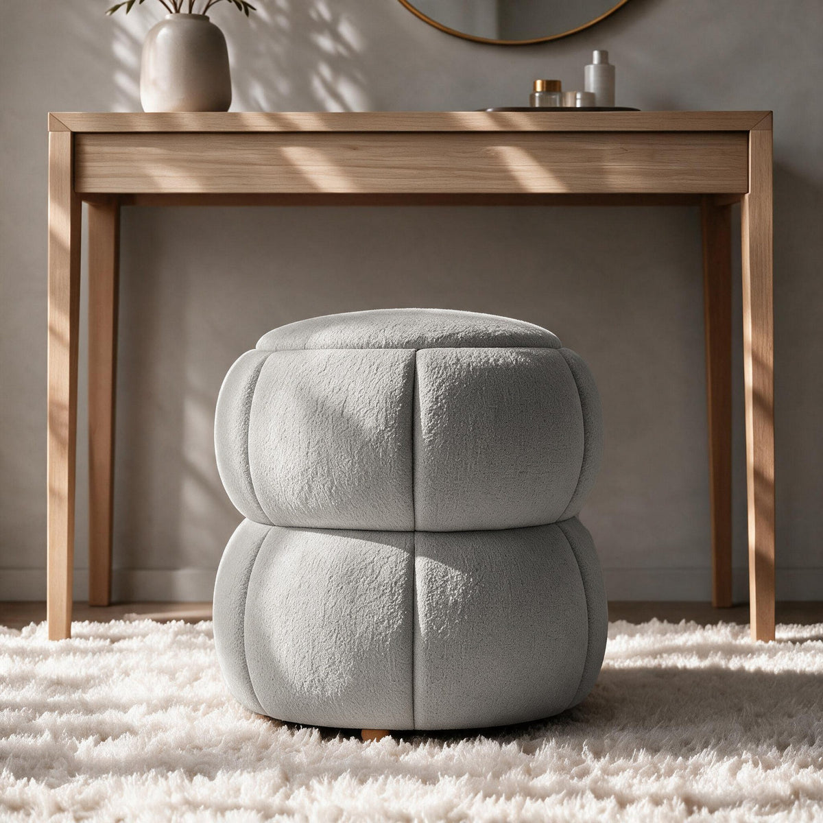 Runder Pouf in Hellgrau mit gestricktem Polyesterbezug, Holzkugelfüssen und gepolstertem Sitzbereich auf hellem Hintergrund fotografiert.