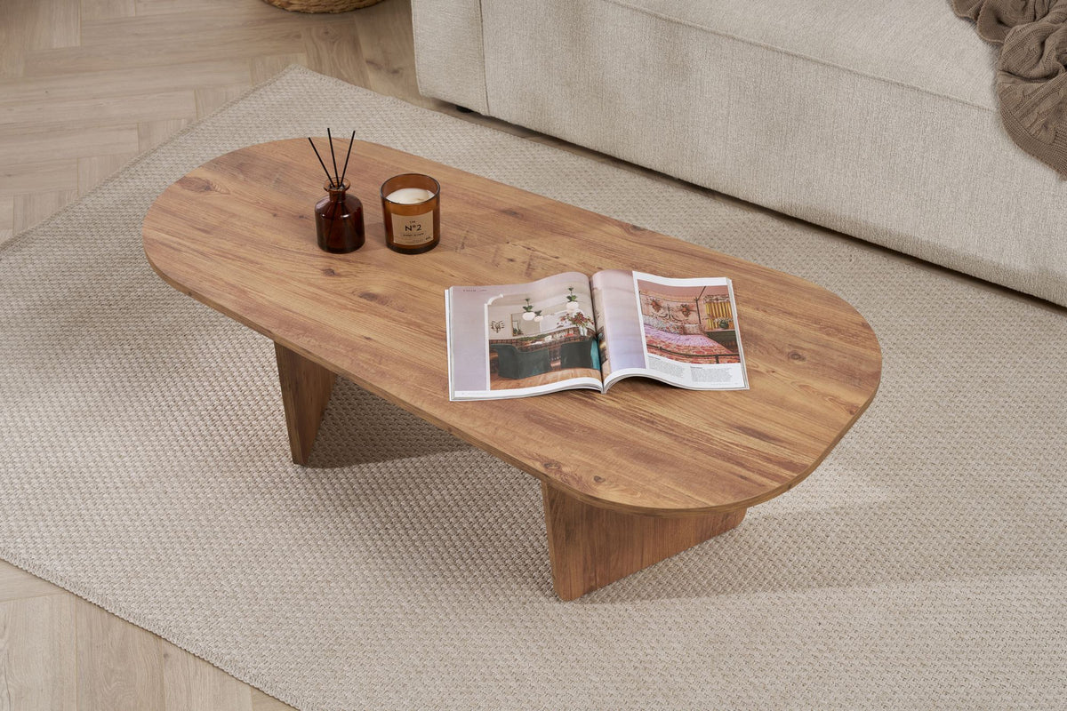 Ovaler Couchtisch in Atlantik-Kiefer Optik von Nordure aus melaminbeschichteter Spanplatte, 130 cm breit, 65 cm tief, 40 cm hoch, im Wohnraum platziert.