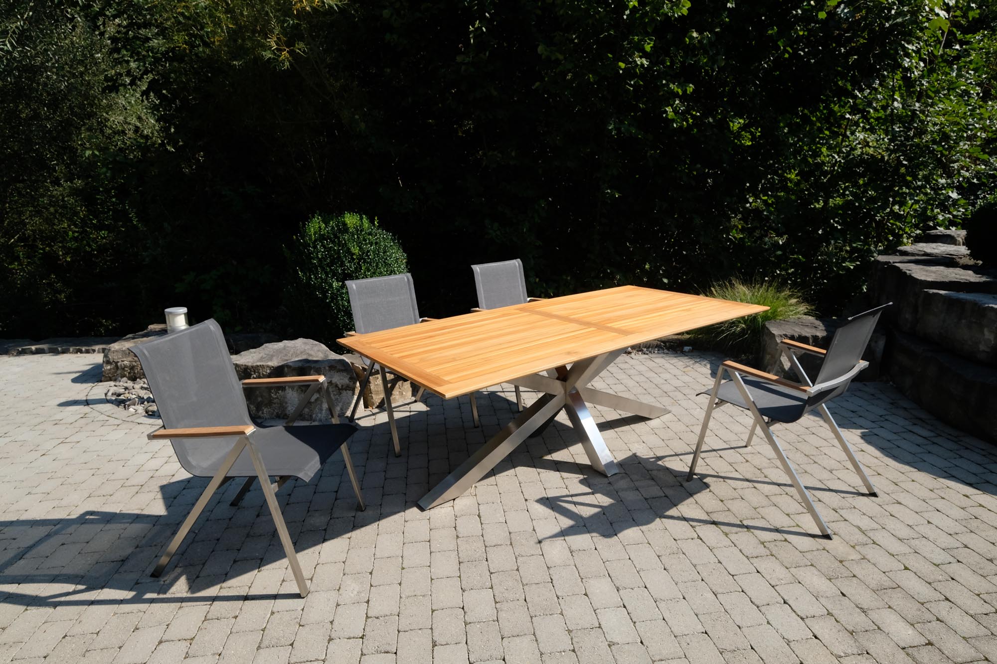 Eleganter Gartentisch Monaco mit stabilen XX-Füßen und hochwertiger Teakplatte, ideal für stilvolle Outdoor-Entspannung.