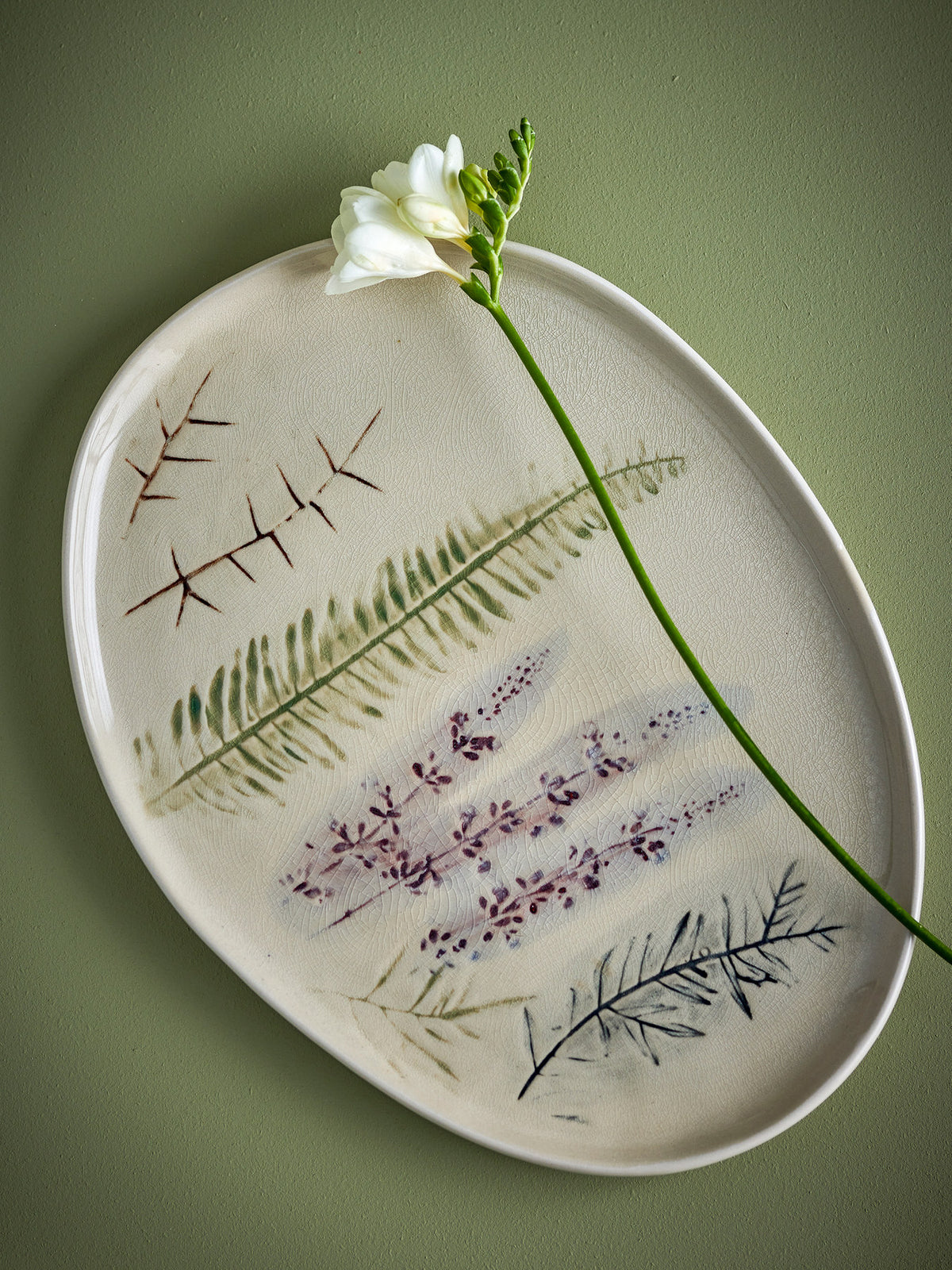 Weisse Servierplatte aus Steingut von Bloomingville mit handgestempeltem Blumenmuster und feiner Krakeleeglasur, länglich geformt.